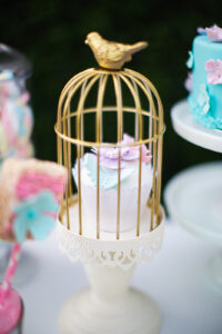 cupcake in a birdcage with pink and blue flowers