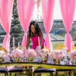 paulette setting up event table, pink roses and candles, pink drapes, pink dress, gold, black and pink table, crystal glasses, outdoor event