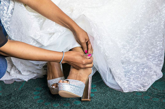 wedding planner tying bride's shoes